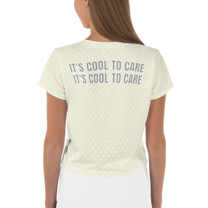 Model in beige short-sleeve cropped t-shirt with white mini polka dot heart print & large grey "IT'S COOL TO CARE" text across back