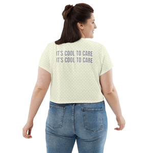Plus-size model in beige short-sleeve cropped t-shirt with white mini polka dot heart print & large grey "IT'S COOL TO CARE" text across back