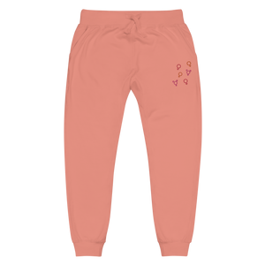 Front view of coral pink 'Girl Power' fleece jogger sweatpants with red, pink, and orange embroidered symbols by maillot.co