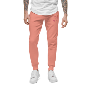 Male model showcasing coral pink 'Girl Power' sweatpants with red, orange, and pink embroidered symbols by maillot.co - unisex sizing fleece joggers