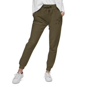 Female model wearing military green 'Girl Power' sweatpants with maroon, black, and grey embroidered symbols by maillot.co - unisex sizing fleece joggers