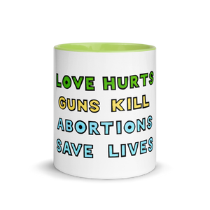 Classic white mug with green lining & green, yellow and blue text reading "love hurts" "guns kill" "abortions save lives"
